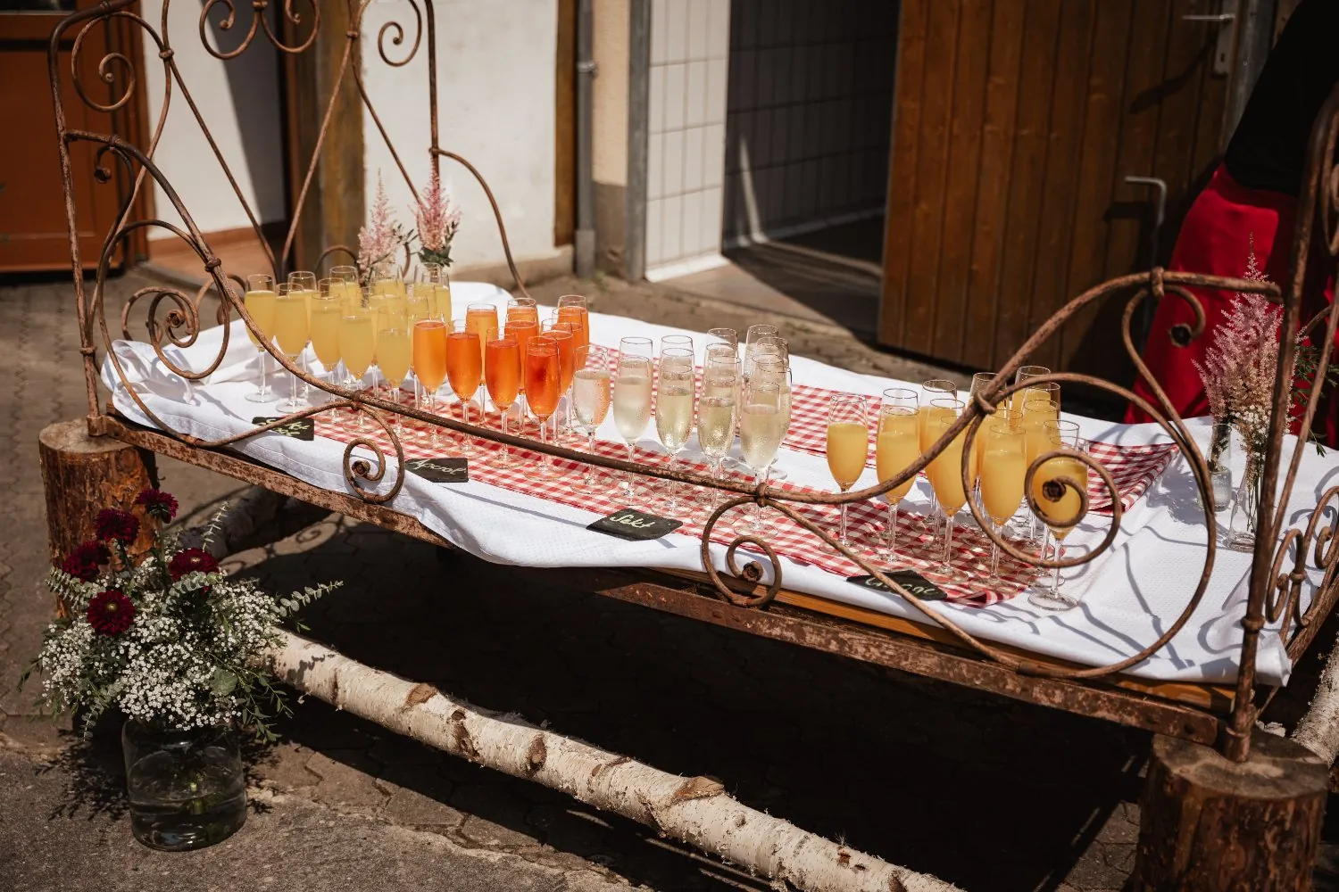 Sektempfang im Hof: Aperol, Sekt und Orangensaft auf einem alten Eisenbett