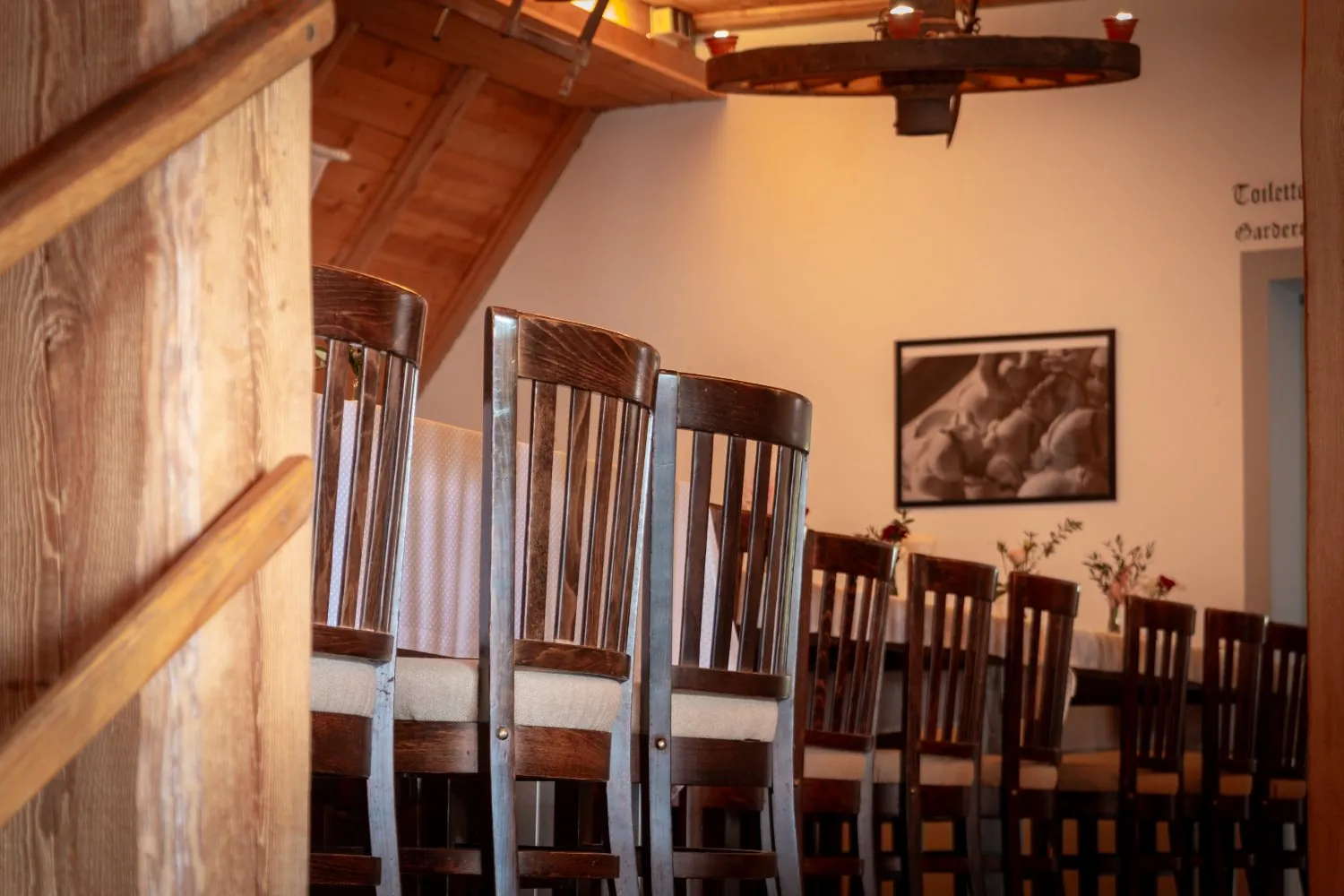 Stuhlreihe an der Tafel mit Wagenradleuchter